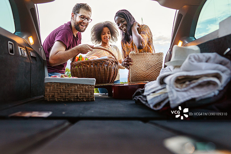 多民族家庭从后备箱取出食物准备野餐图片素材