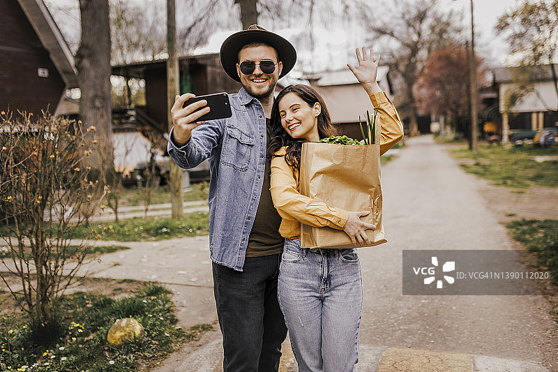 情侣提着装满食品杂货的购物袋自拍图片素材
