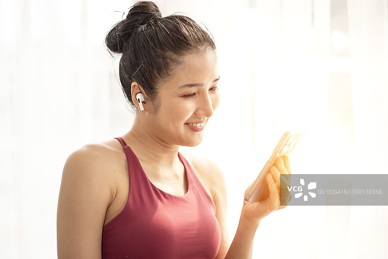 戴着智能手机耳机在家与朋友兴奋交谈的亚洲女孩图片素材