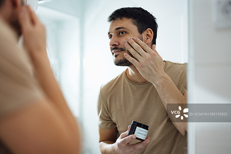 在浴室涂抹面霜的英俊男人图片素材