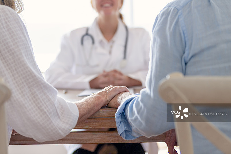 中年夫妇在医生办公室手牵着手图片素材