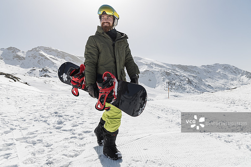 在阳光明媚的日子里带着滑雪板行走的快乐年轻人图片素材