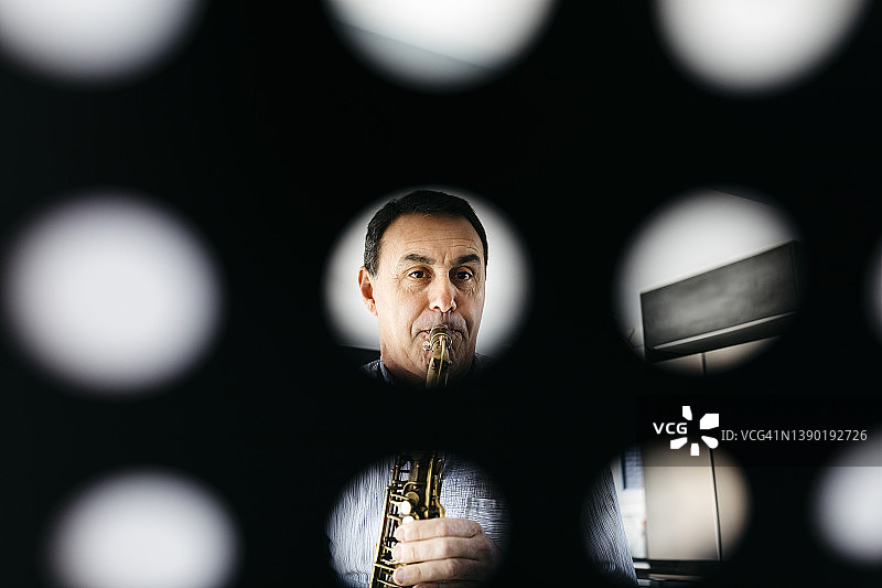 透过乐谱架看到的音乐家吹奏萨克斯管图片素材