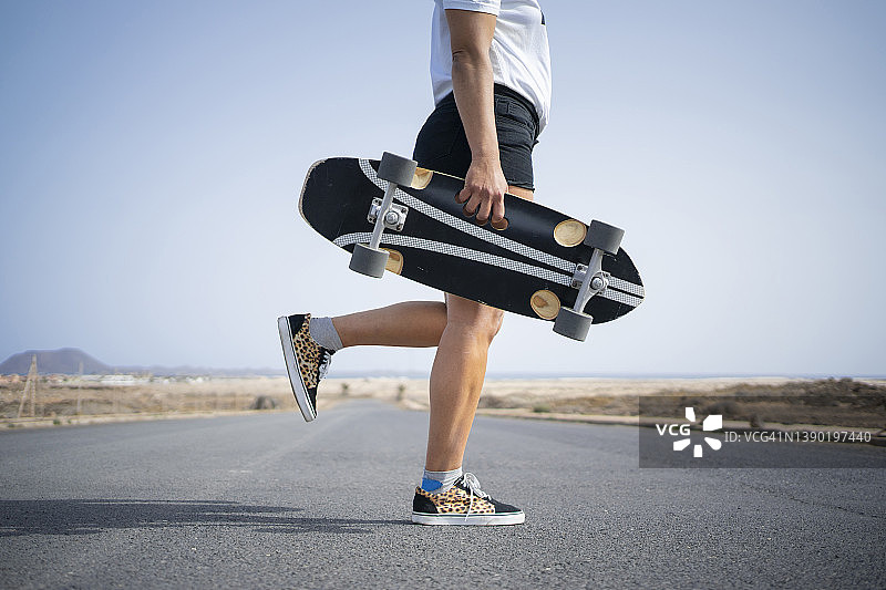 在路上单腿站立的滑板女子图片素材