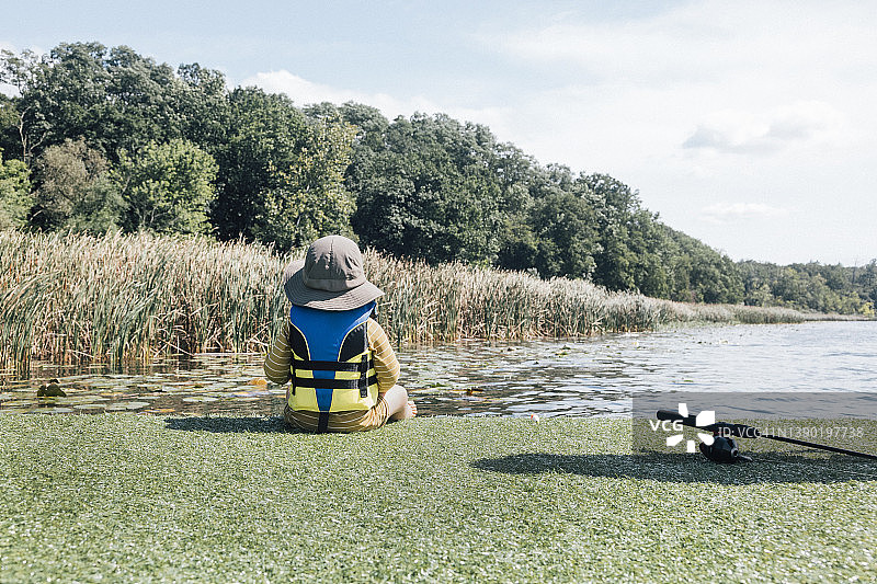 阳光明媚的日子里，男婴坐在河岸边图片素材