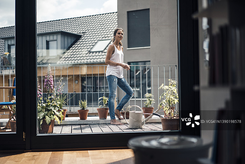 透过玻璃窗看到的站在阳台上的女人图片素材