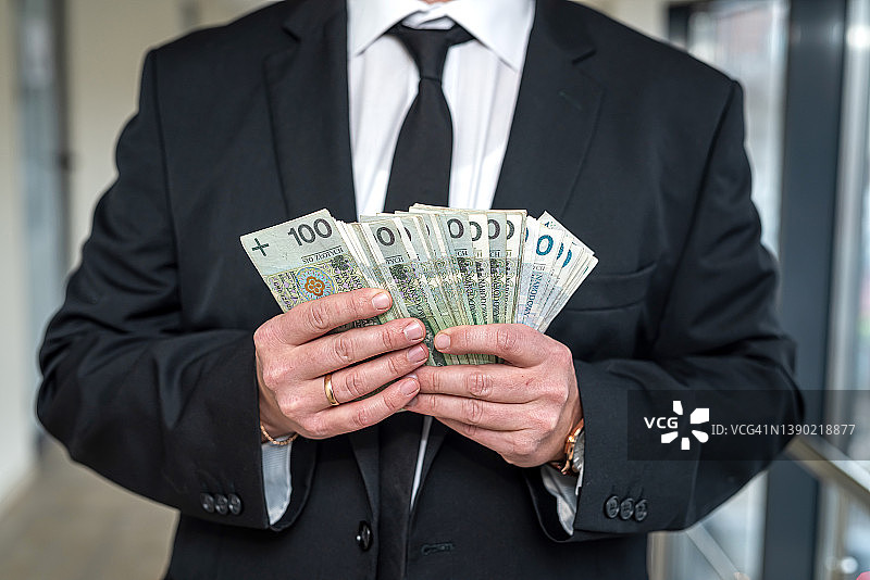 一位优雅的男人手中拿着波兰兹罗提图片素材