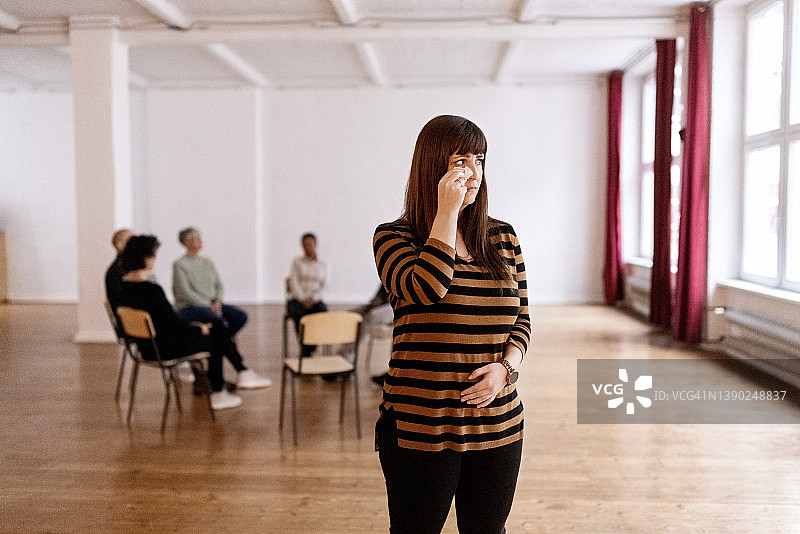 悲伤的女人与团体治疗的参与者分开站立图片素材
