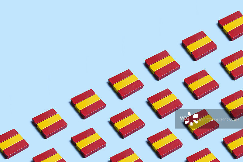 蓝色背景上由木制玩具积木组成的许多西班牙国旗图片素材