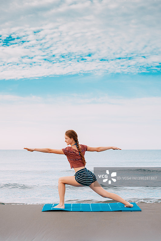 在海滩上做瑜伽的年轻红发女子图片素材