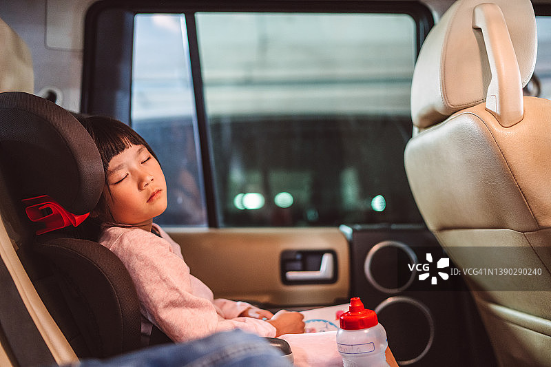 可爱的小女孩在汽车儿童座椅中小憩图片素材