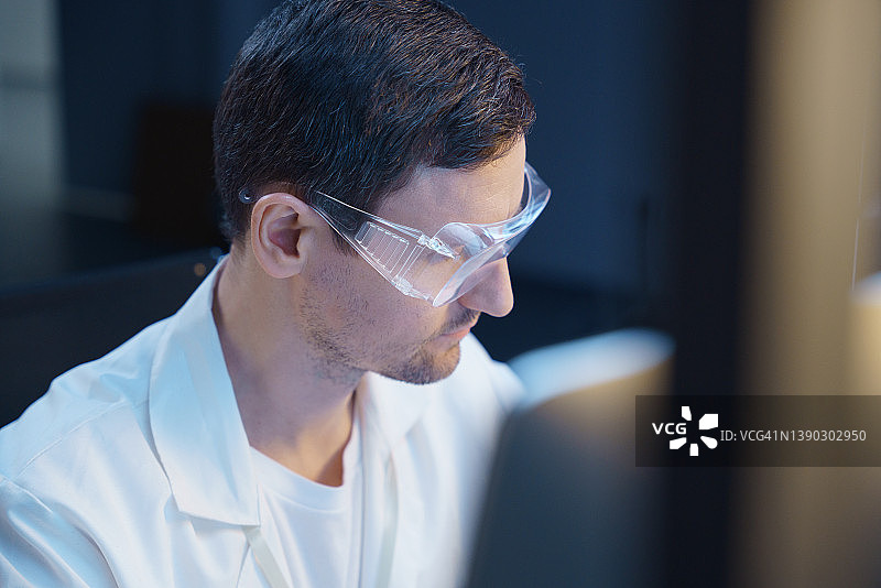 身穿实验服和防护眼镜的白人科学家在现代实验室中半转身图片素材