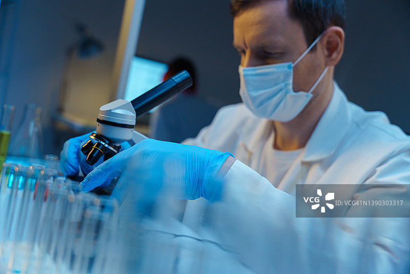 穿实验服的白人男子在现代实验室用显微镜工作图片素材
