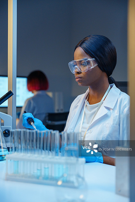 年轻漂亮的非裔女实验助理在现代实验室工作图片素材