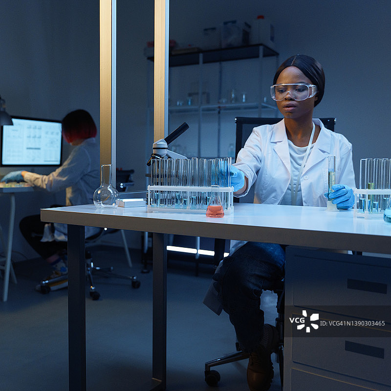 在现代实验室里，一位年轻漂亮的非裔美国女科学家穿着实验服进行化学测试图片素材