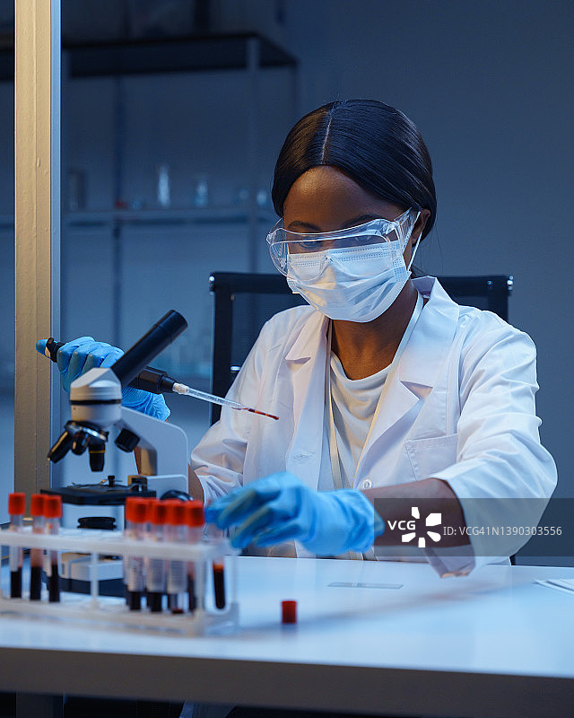 血液分析过程：年轻的非洲裔美国实验室助理正在使用试管中的血液样本图片素材