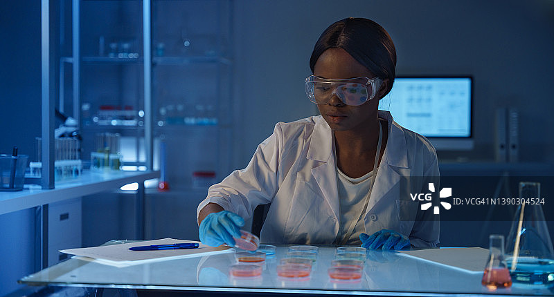 在现代实验室使用培养皿的非洲青年女科学家图片素材