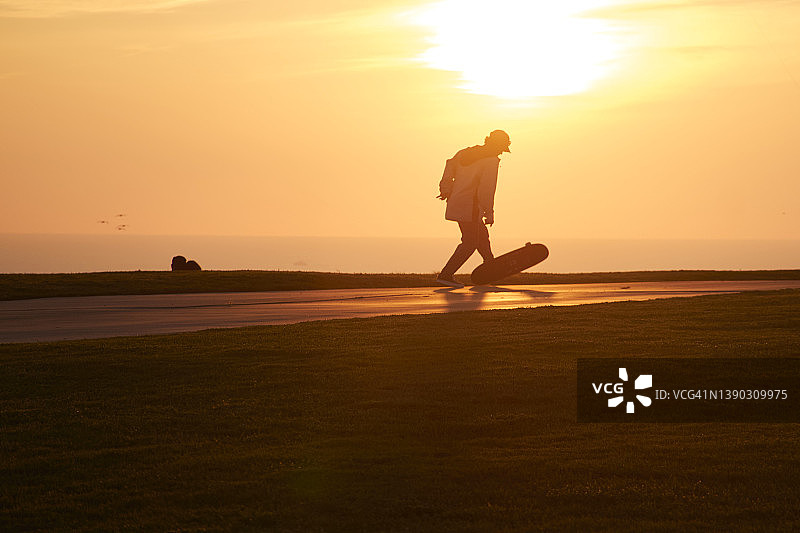 在日落时分玩滑板的中年男人图片素材