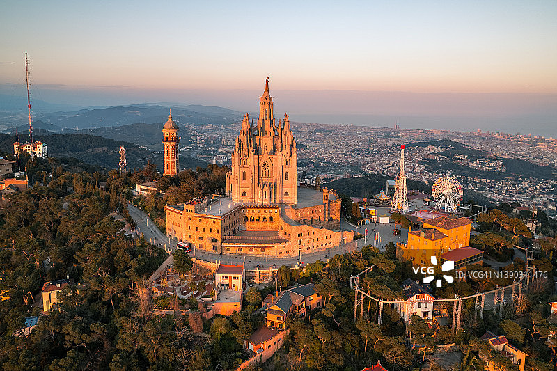 西班牙加泰罗尼亚巴塞罗那空中俯瞰蒂比达博圣心堂和游乐园日落图片素材