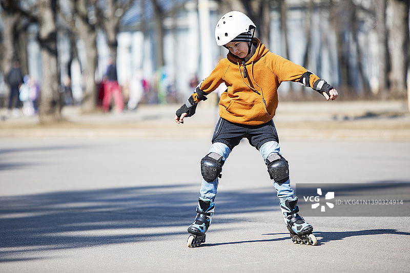小男孩戴着头盔和护具在公园里玩轮滑图片素材
