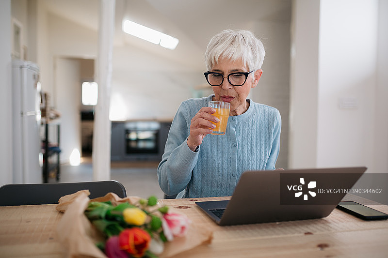在家中使用笔记本电脑的年长女性图片素材