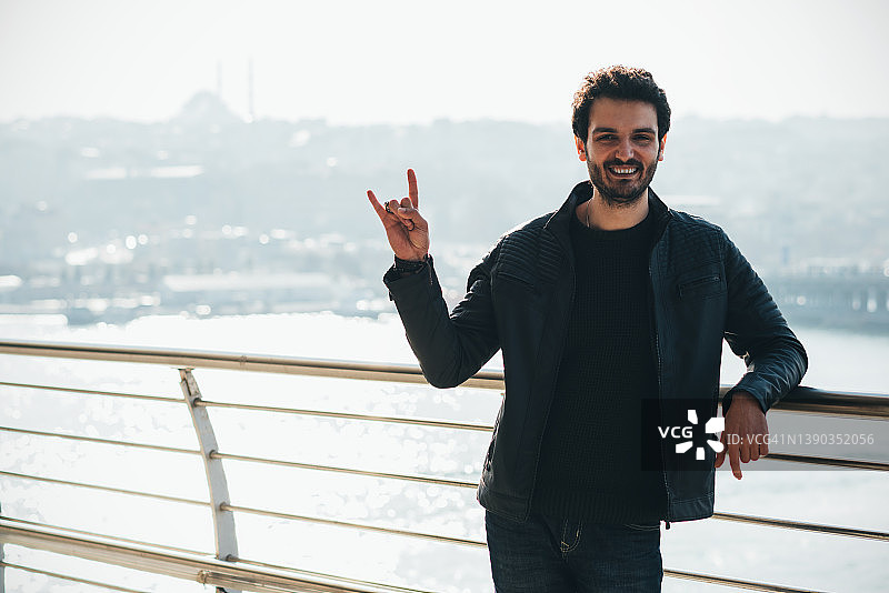 留着胡须的英俊男人用手指做出摇滚手势图片素材