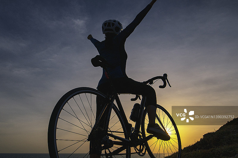 骑自行车的女子在日落时锻炼后举起自行车图片素材