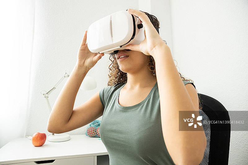 女人在家中观看模拟场景，手持VR眼镜图片素材