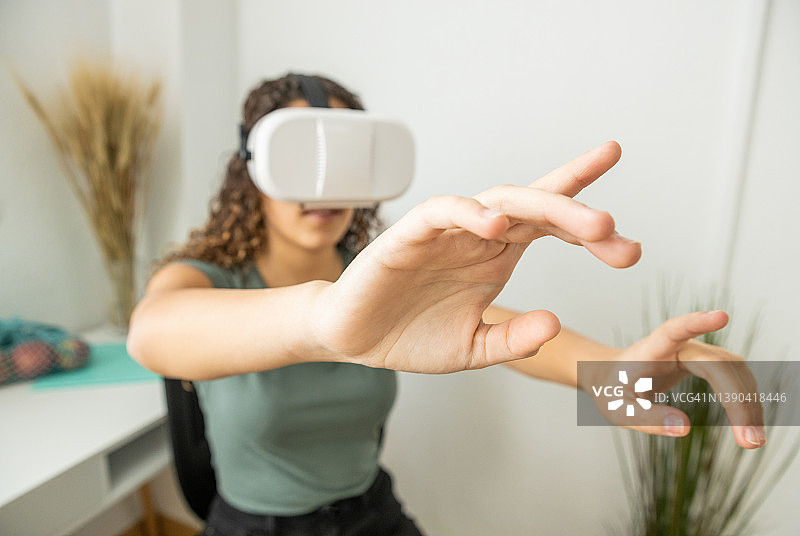 戴VR眼镜在家玩游戏的女人伸展双臂图片素材