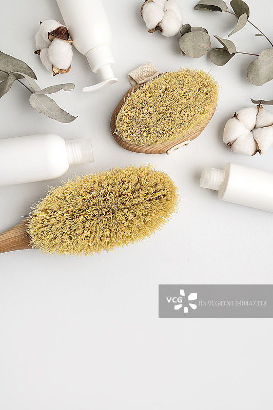 木制身体按摩刷、化妆品瓶和桉树枝图片素材