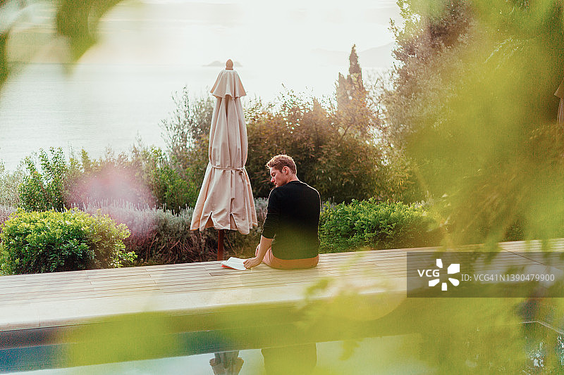 在泳池边看书的年轻人图片素材