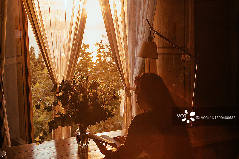 在阳光明媚的房间里阅读的女人图片素材