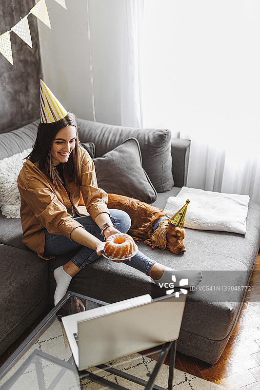 女人与狗庆祝生日，笔记本电脑视频通话图片素材