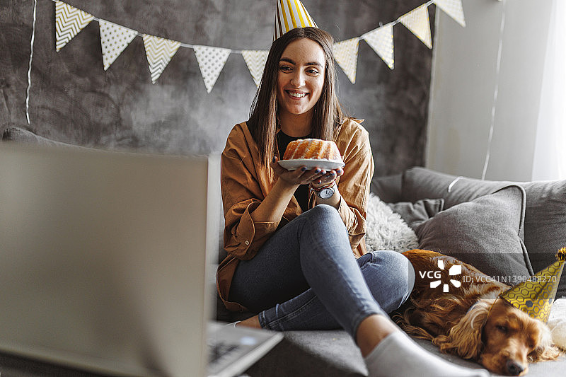 女人与狗庆祝生日，笔记本电脑视频通话图片素材