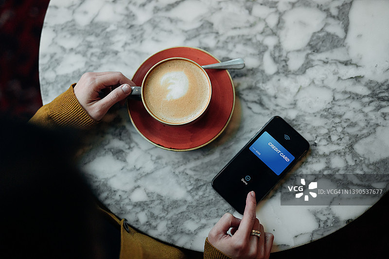 咖啡馆内使用非接触式支付的女子俯视图图片素材