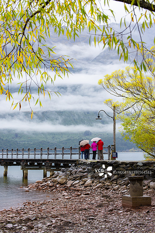 在新西兰皇后镇格莱诺基，秋日晨雾中的码头桥上的游客图片素材