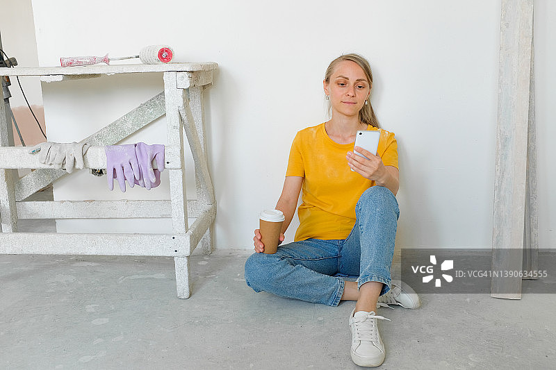 建筑女博主在镜头前广播或展示，喝着咖啡。 建筑工具在附近。 专业维修和施工的概念，爱好。 视频通话，视频会议，虚拟活动。图片素材