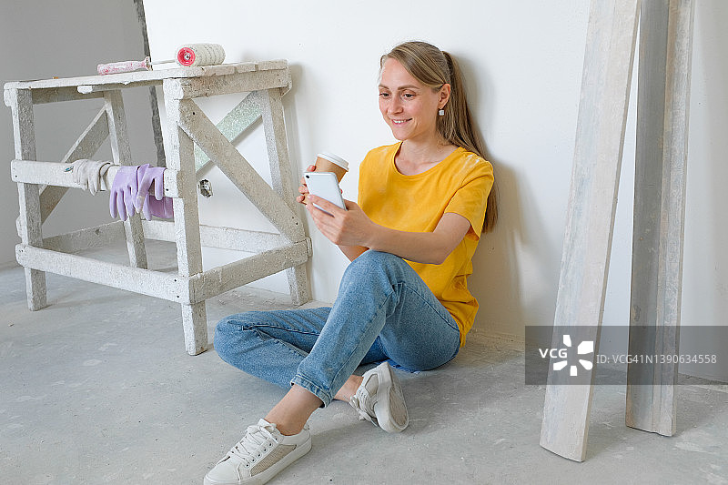 建筑女博主在镜头前广播或展示，喝着咖啡。 建筑工具在附近。 专业维修和施工的概念，爱好。 视频通话，视频会议，虚拟活动。图片素材