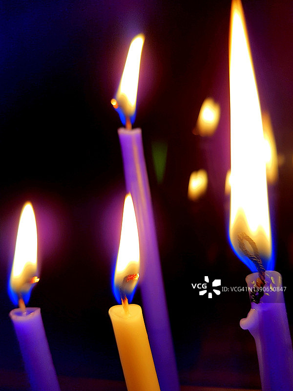 夜晚中点燃的三根紫色蜡烛和一根黄色蜡烛图片素材