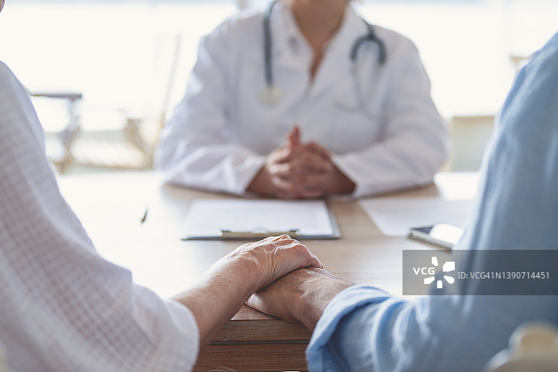 中年夫妇在医生办公室手牵着手图片素材