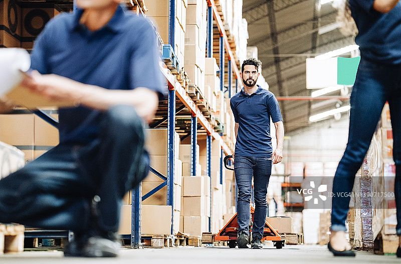 仓库 работ人员用托盘车拉包裹图片素材