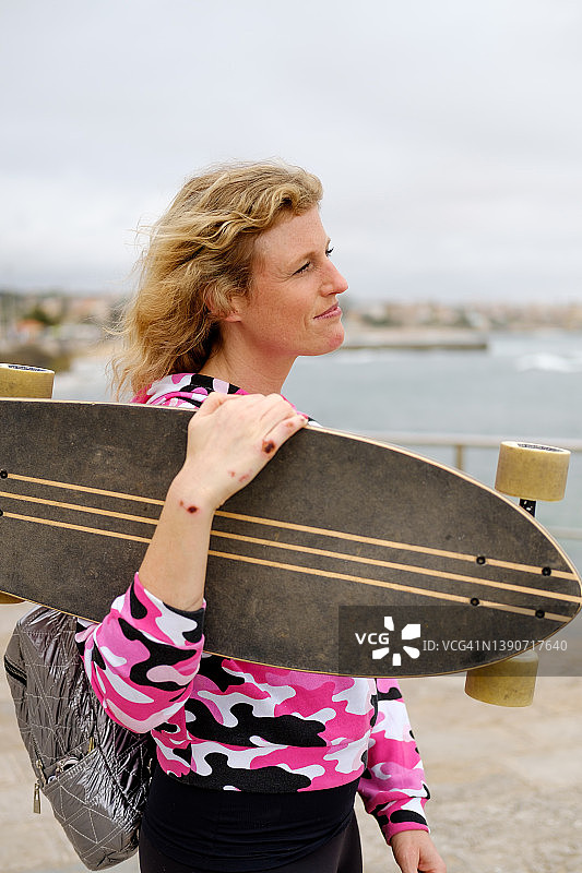 手拿滑板，手上有摔伤痕迹的女人图片素材