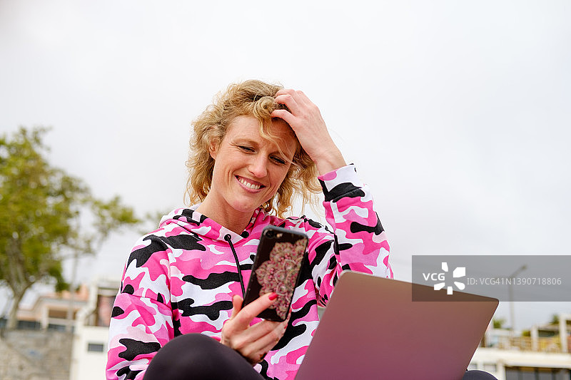 在海滩上使用手机和笔记本电脑的女人图片素材