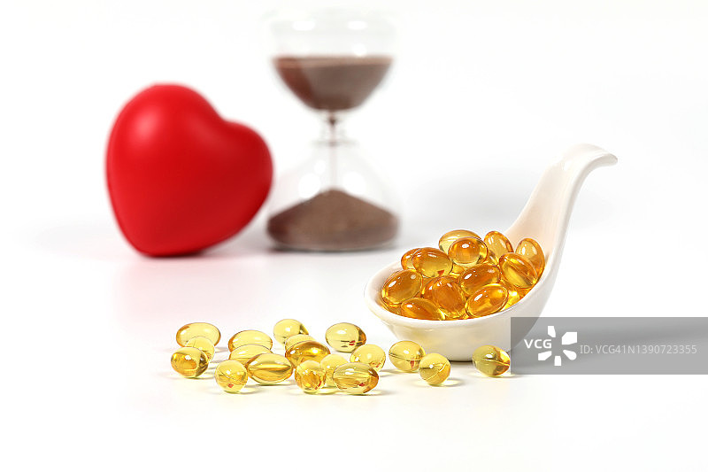 鱼油，健康维生素，鳕鱼肝油Omega 3和DHA，身体护理黄色透明药丸，带有沙漏图片素材