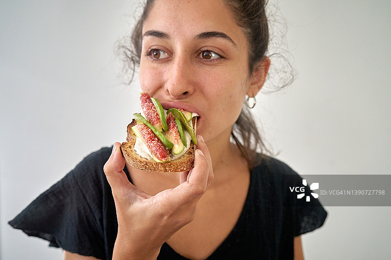 年轻女子吃牛油果吐司配无花果图片素材