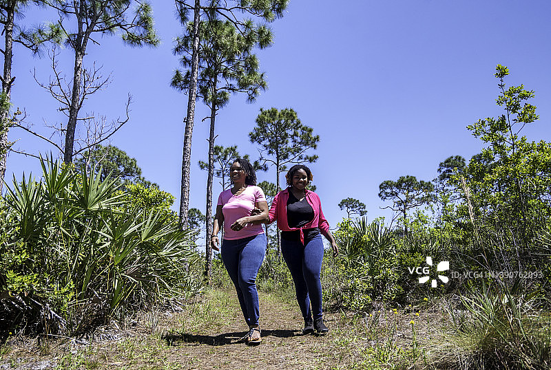快乐的成年母亲和青少年女儿在热带树林地区散步，家庭团聚图片素材
