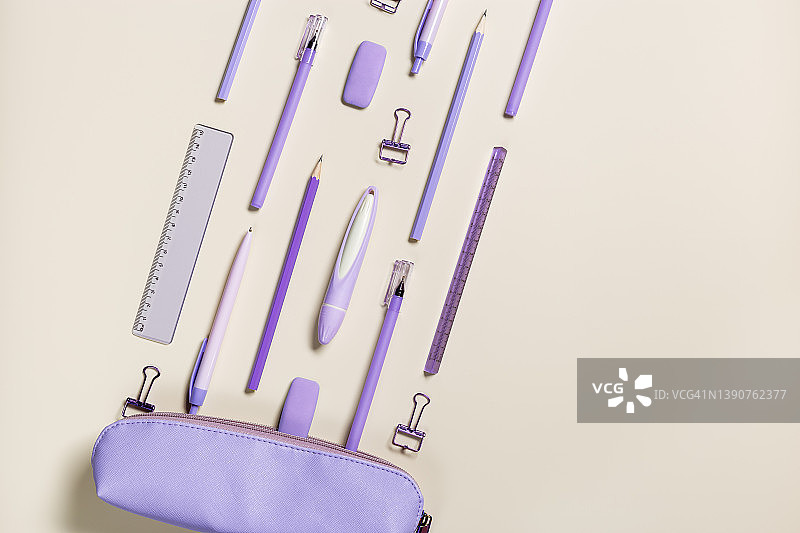 长春花蓝色办公用品：铅笔、钢笔、回形针和橡皮从铅笔盒中飞出，米色背景上的返校季文具用品，带复制空间图片素材