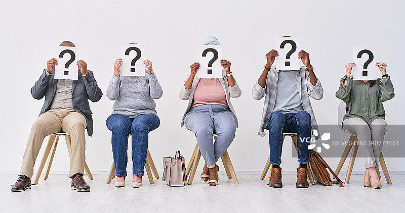 一群商务人士坐着，举着问号等待面试图片素材