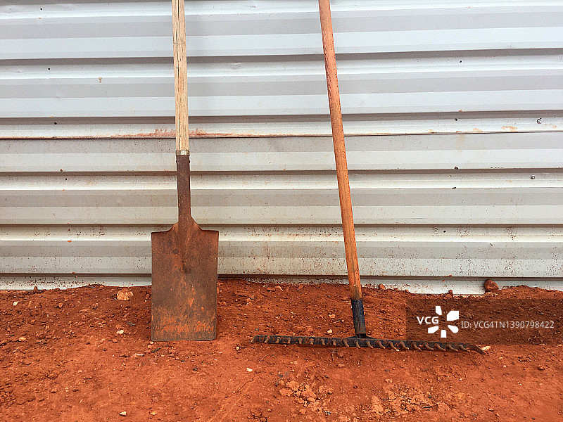 靠在瓦楞墙上的铁锹和耙子图片素材