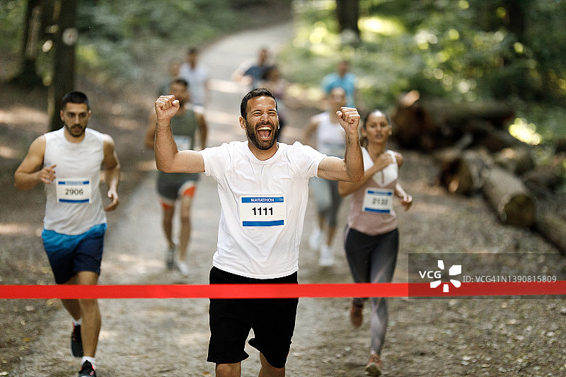 成功的马拉松运动员张开双臂冲过终点线。图片素材